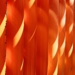 a close up of an orange wall with long shadows