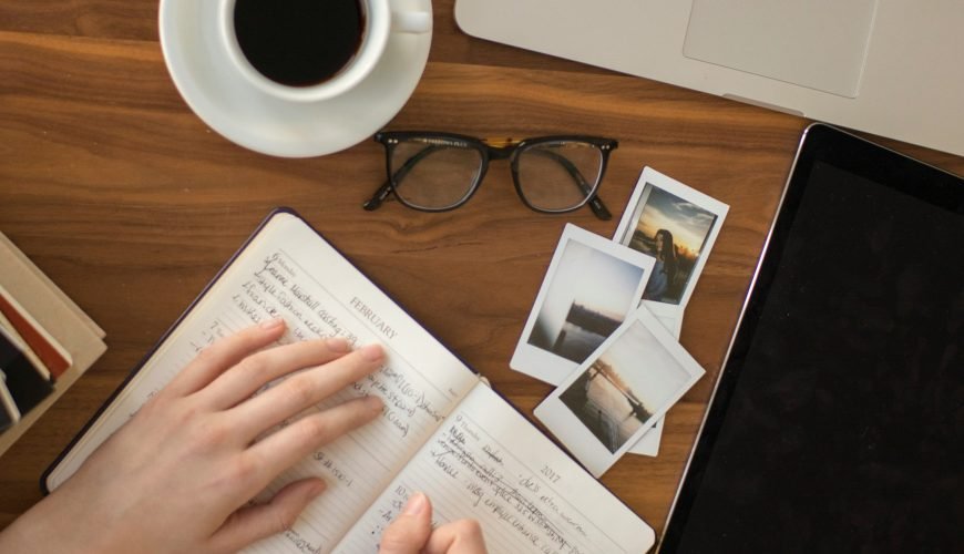 person holding ballpoint pen writing on notebook